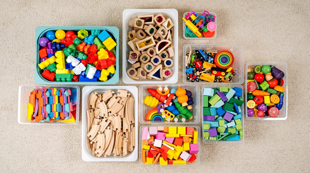 A collection of wooden toys neatly organized in clear plastic containers.