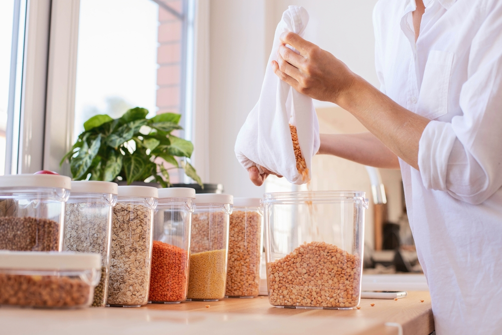 Woman preserving food in glass jars on a kitchen counter.