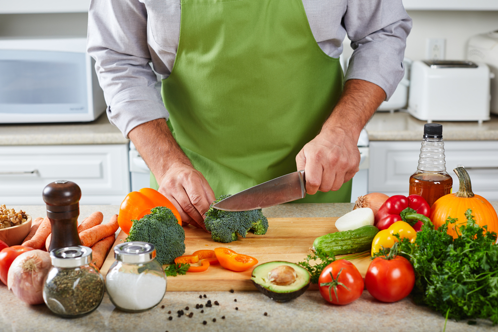 A man slicing vegetables on a wooden cutting board.