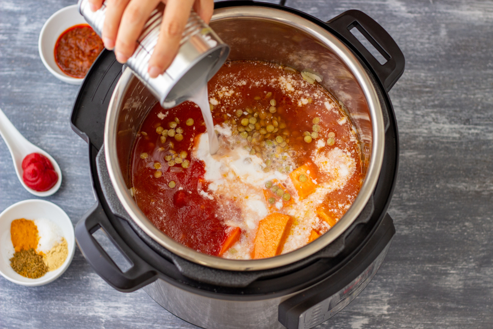 A person pouring sauce into an Instant Pot, preparing a delicious meal.