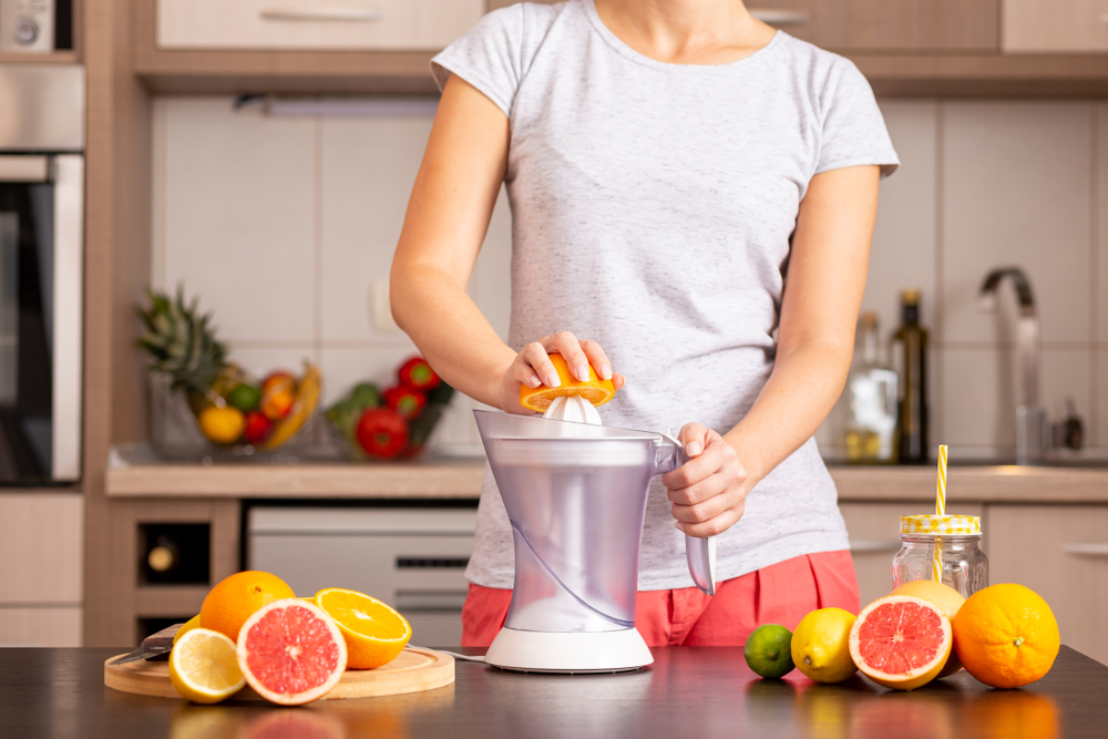  A woman blending fruits in a juicer to make fresh juice.