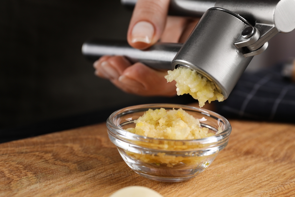 Chef making garlic paste with garlic pressure