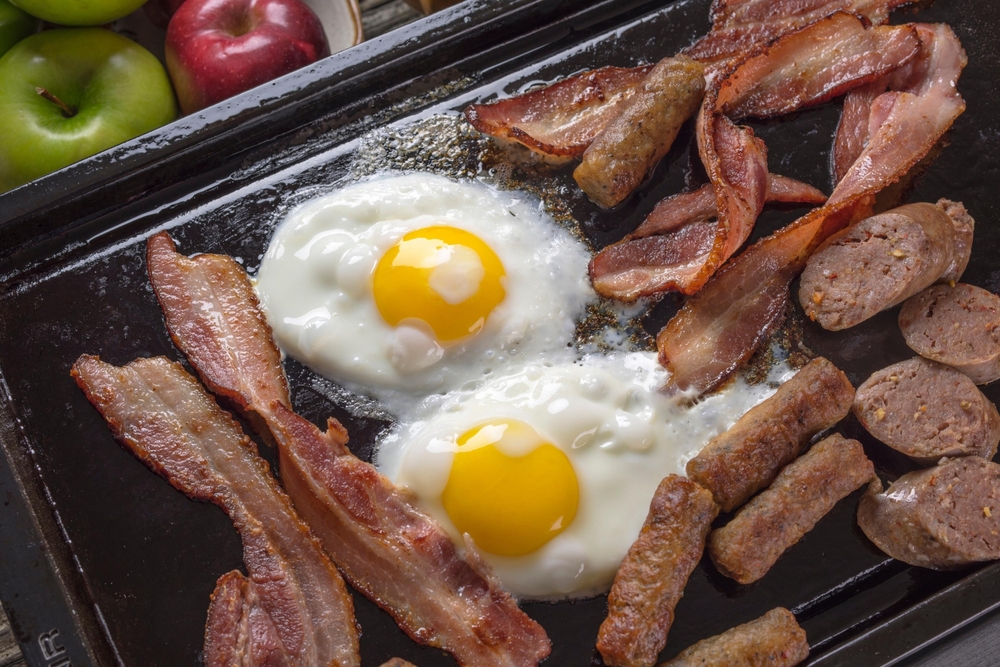 Sizzling Sausage, Eggs, and Bacon in a Cast Iron Pan, a Hearty Breakfast