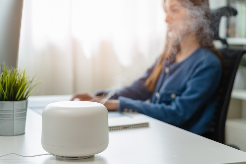 A woman focused on her laptop, with an humidifier placed on the table, enhancing her workspace .