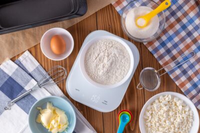 Flour on digital kitchen scale with cookie ingredients for baking on wooden table, weight 150 g