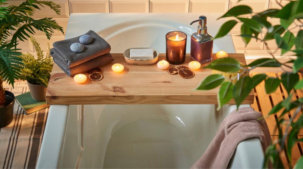 Modern bath room and spa center on the white tub wooden table. Candle soap and towel style with vase of plant. White marble background wall.