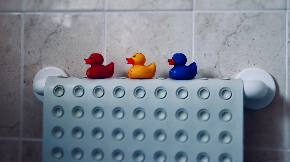 Plastic ducks in a row sitting on a bath mat