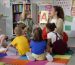 Female teacher hold flashcard with letter a teaching preschool kids alphabet. Diverse pupils of primary school sit on floor with teacher having alphabet lesson