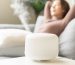 Modern air humidifier during relax or rest, happy blurred asian young woman, girl enjoying aromatherapy steam scent from essential oil diffuser comfortable in living conditions room,apartment at h