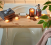 Modern bath room and spa center on the white tub wooden table. Candle soap and towel style with vase of plant. White marble background wall.