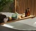 Wooden bath tray with candle, air freshener and bathroom amenities on tub indoors